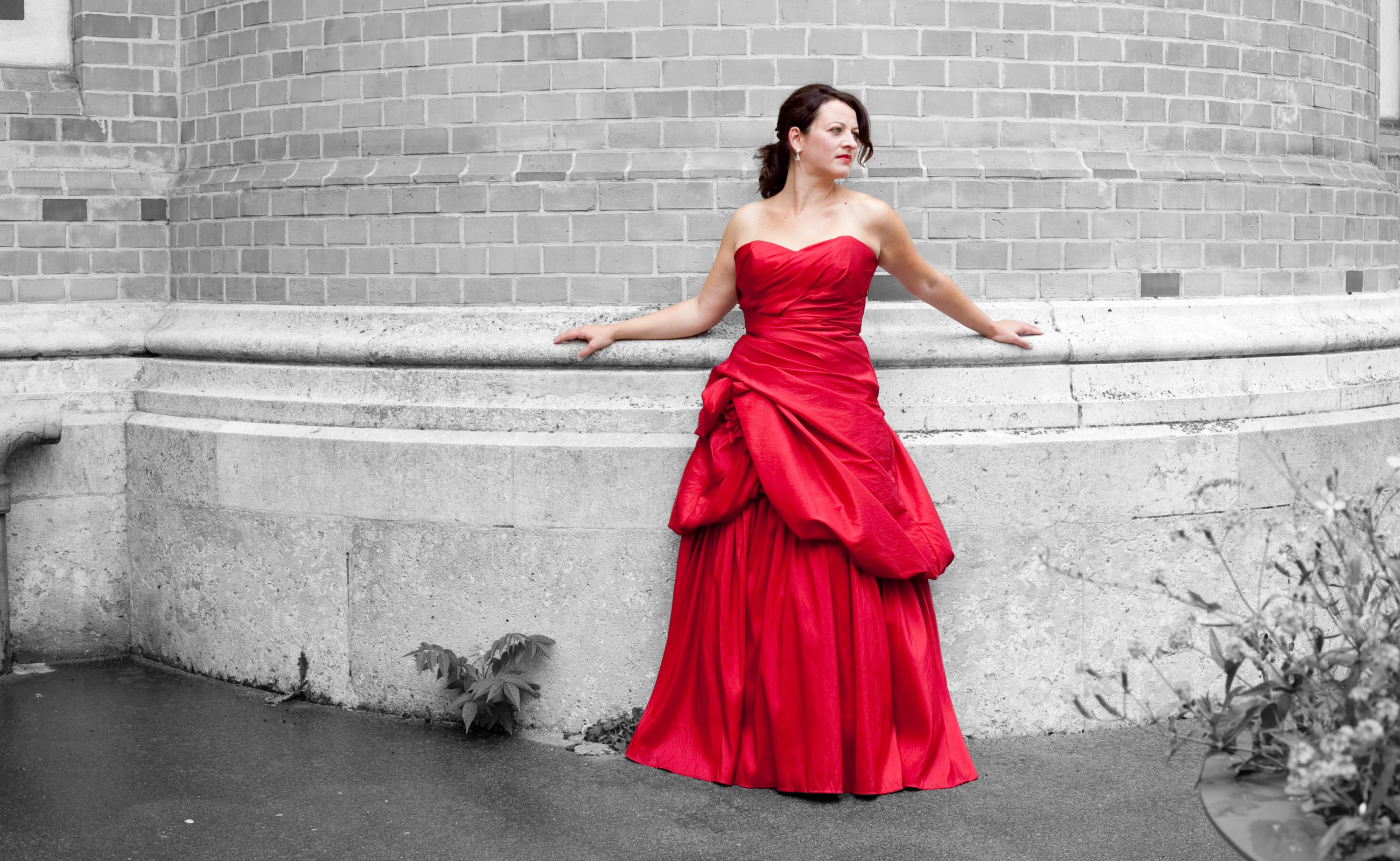 Eva Kumpfmüller in rotem Kleid vor einer Ziegelmauer